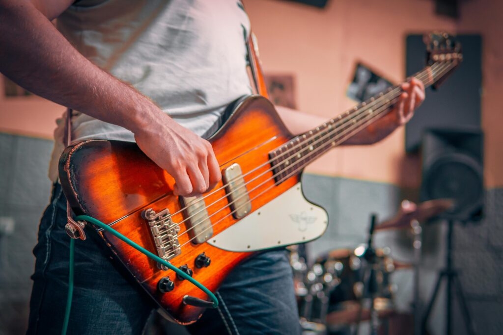 Musician strumming a vintage electric bass guitar during a live performance.