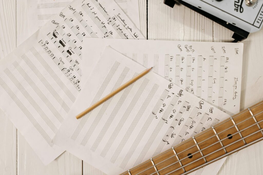 Close-up view of sheet music, a guitar, and a pencil, ideal for music creation and inspiration.